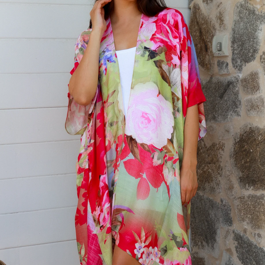 Woman wearing a colorful floral kimono against a stone wall.