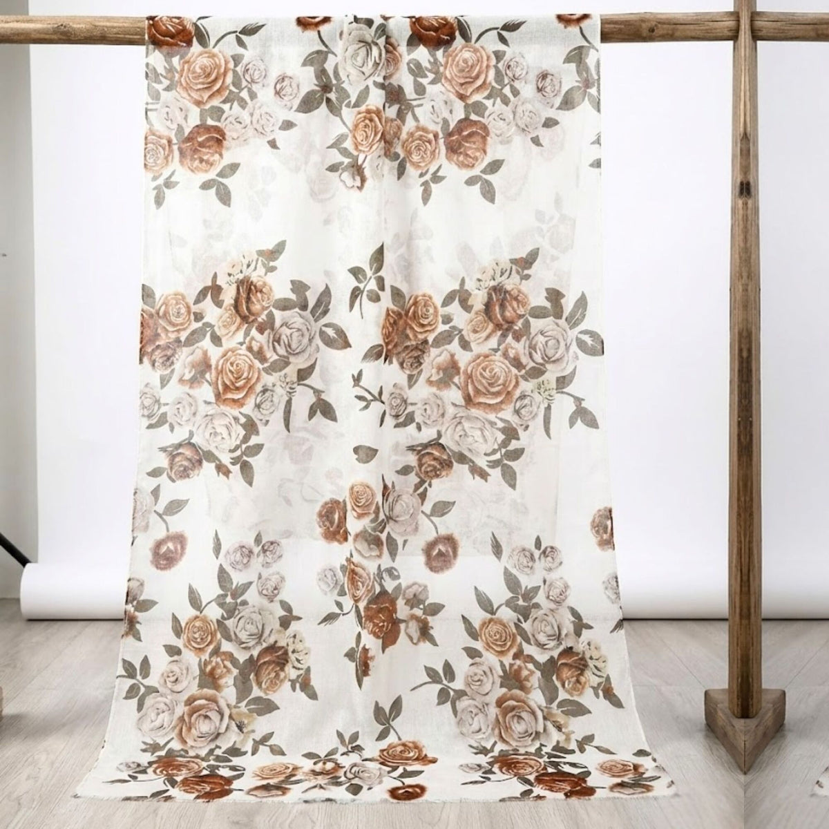 Floral patterned fabric draped over a wooden rack on a light wooden floor.