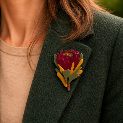 Person wearing a dark green coat with a colorful flower brooch on a blurred background