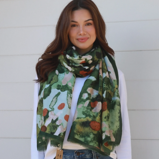 woman wearing jeans, long sleeve white top and a dark green floral scarf