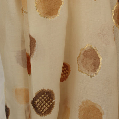 A close-up of a cream-colored sheer scarf with metallic gold and brown watercolor-style circular patterns.