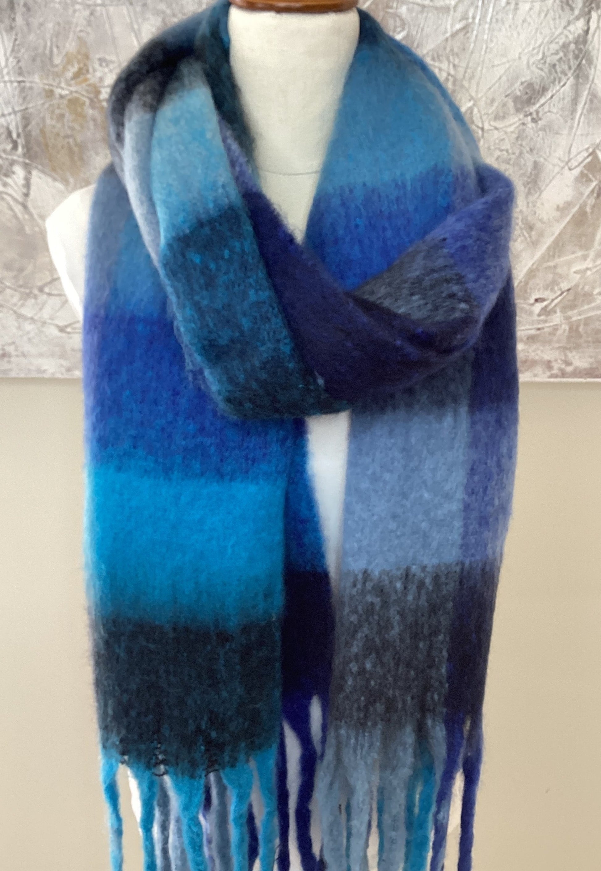 a large oversized scarf that has a bright blue check pattern and chunky tassels