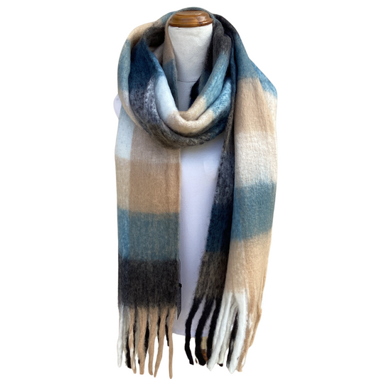 A soft, oversized striped scarf with fringe ends, draped on a white mannequin torso. The scarf features horizontal stripes in shades of blue, beige, gray, and black.