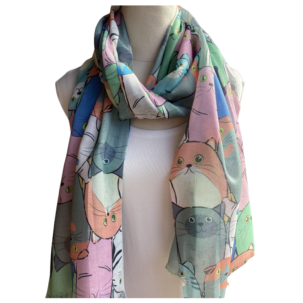 a ladies scarf that has large cat faces in colours of grey, blue, apricot and pink.