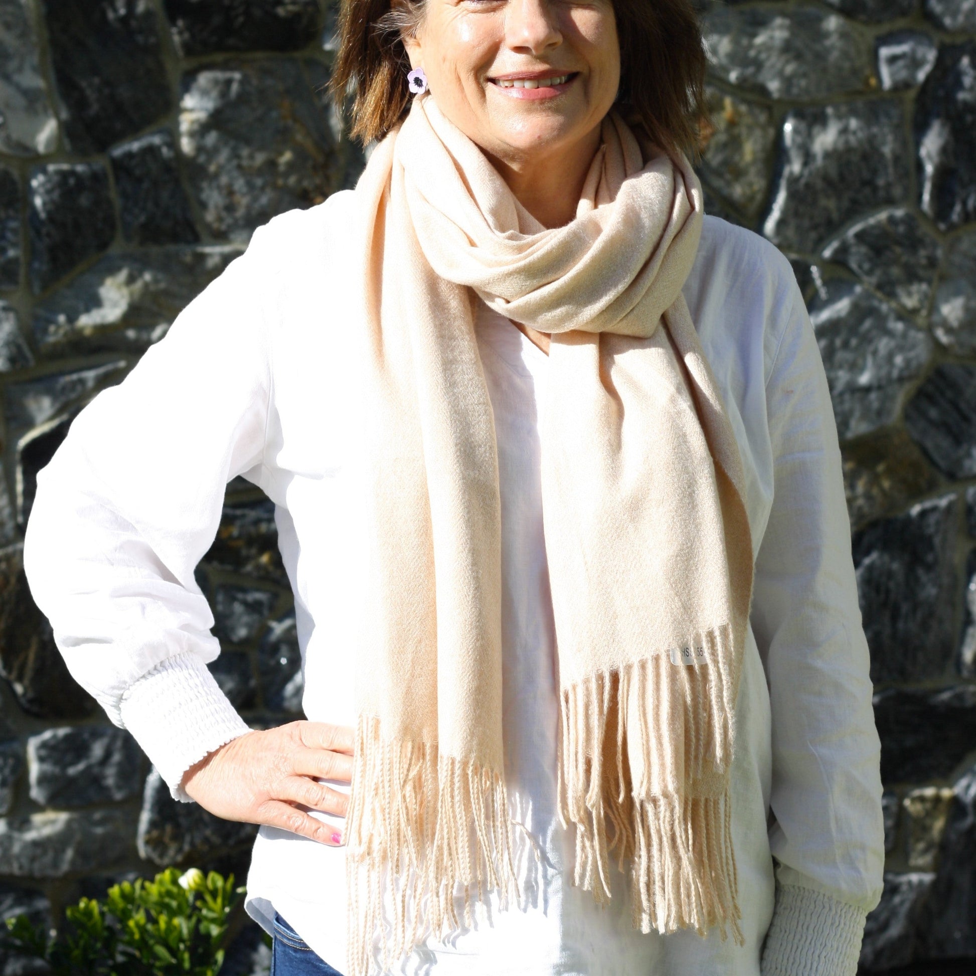 a lady wearing a plain winter wool scarf that is a dark cream colour with tassels