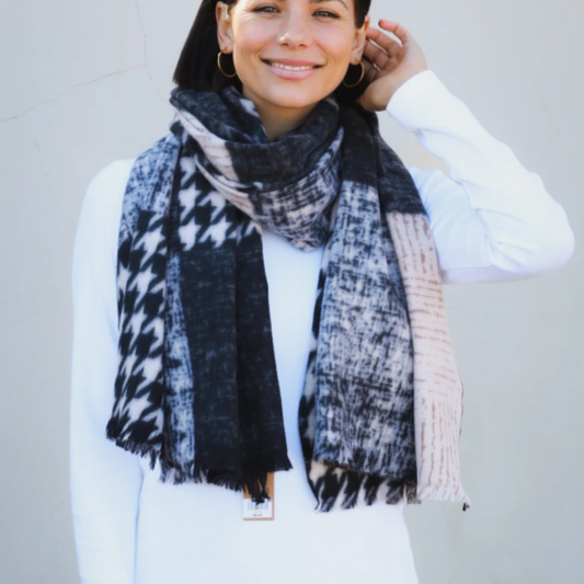 a lady wearing a soft winter scarf that has a patchwork pattern in the colours of black, grey and cream