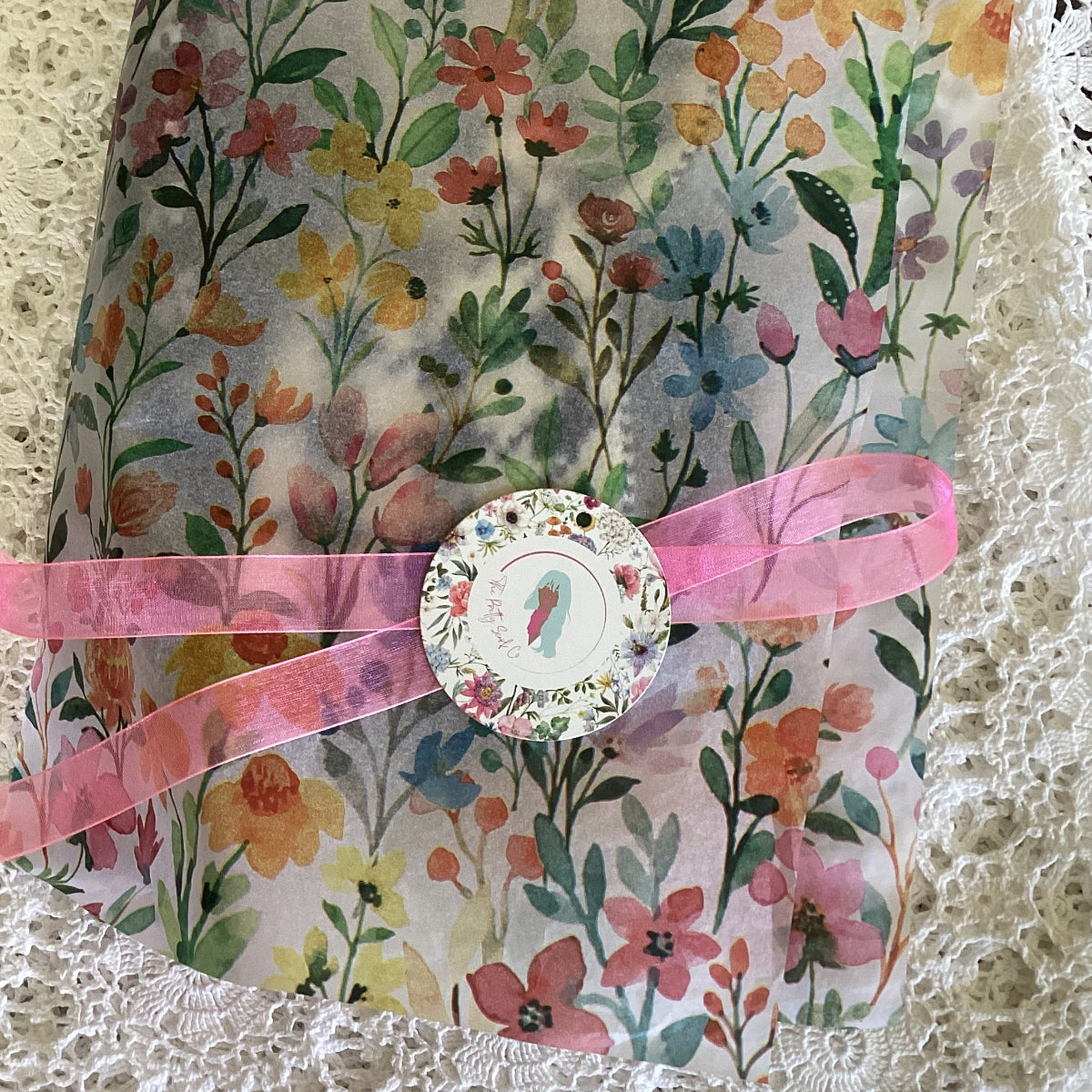 Floral-patterned tissue paper with a pink ribbon and round gift tag
