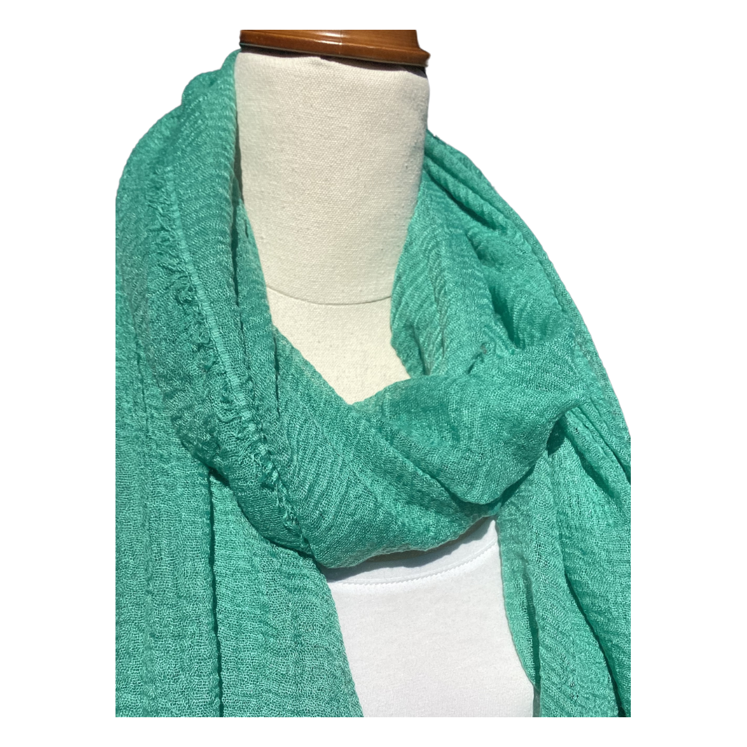 a plain ladies scarf that is jade green in colour and has a textured weave and frayed edges