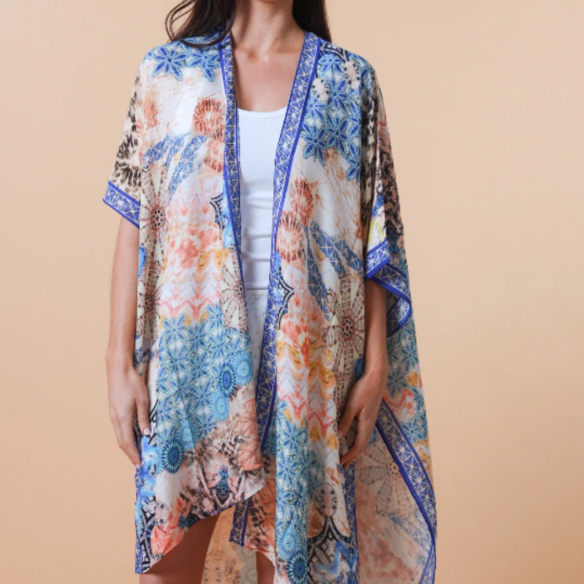 Woman wearing a blue abstract design kimono over a plain top against a beige background
