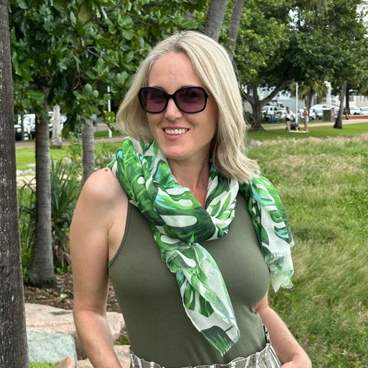 a lady wearing a scarf that has a green monstera leaf pattern.