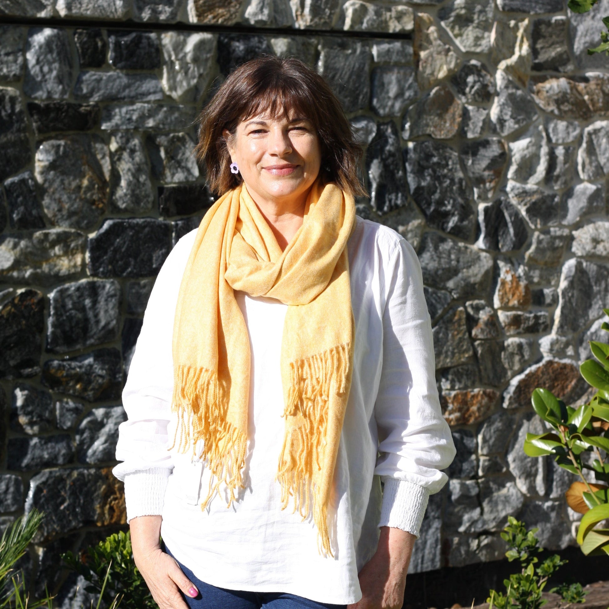 a lady wearing a soft winter wool scarf in a dark yellow mustard colour with tassels