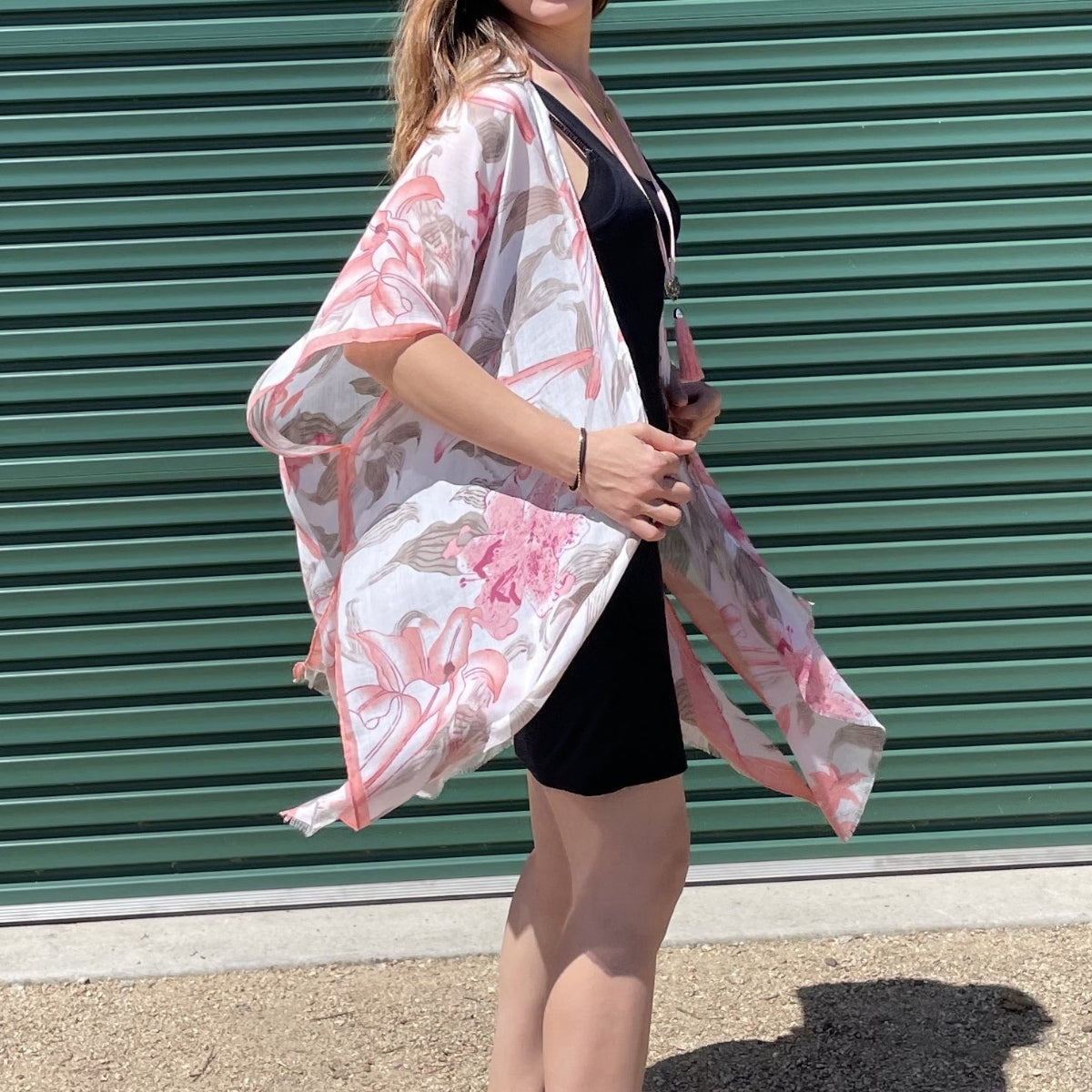 Woman wearing a floral kimono in front of a green metal shutter.