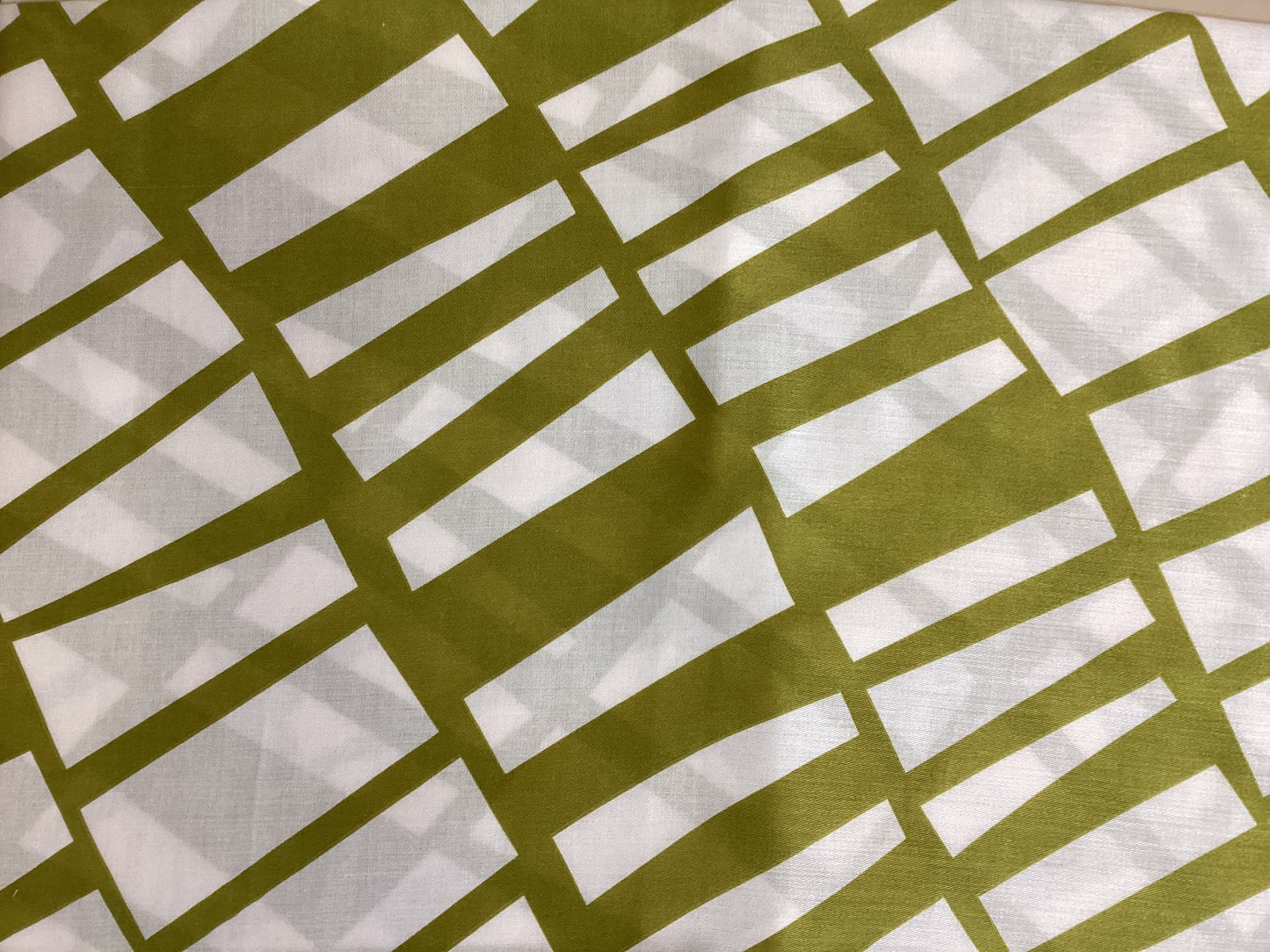 a close up of a ladies scarf that has a pistachio coloured linear pattern on a warm white background