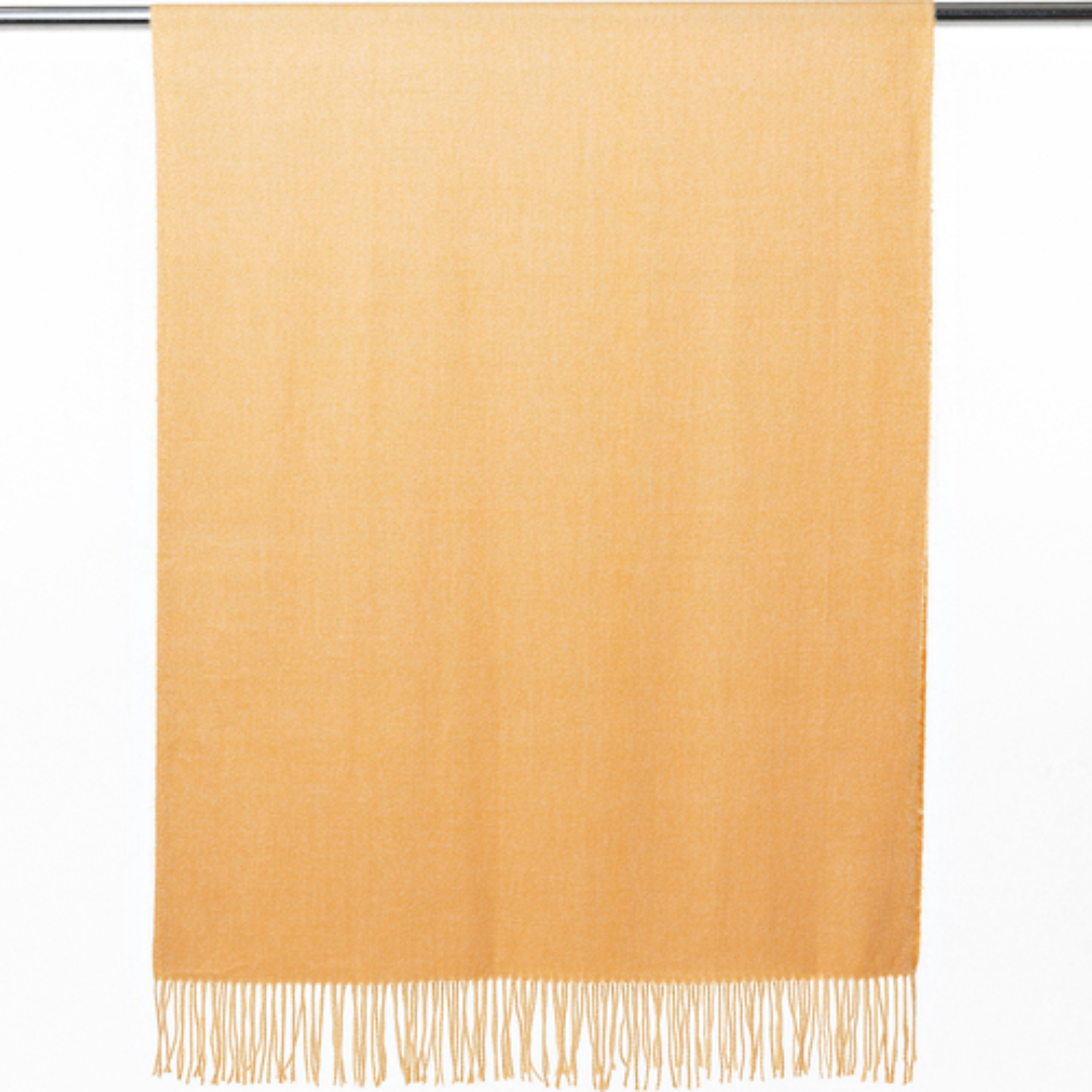 A soft and warm ladies scarf that is plain honey mustard colour with tassels. The scarf is hanging so you can see the tassels.