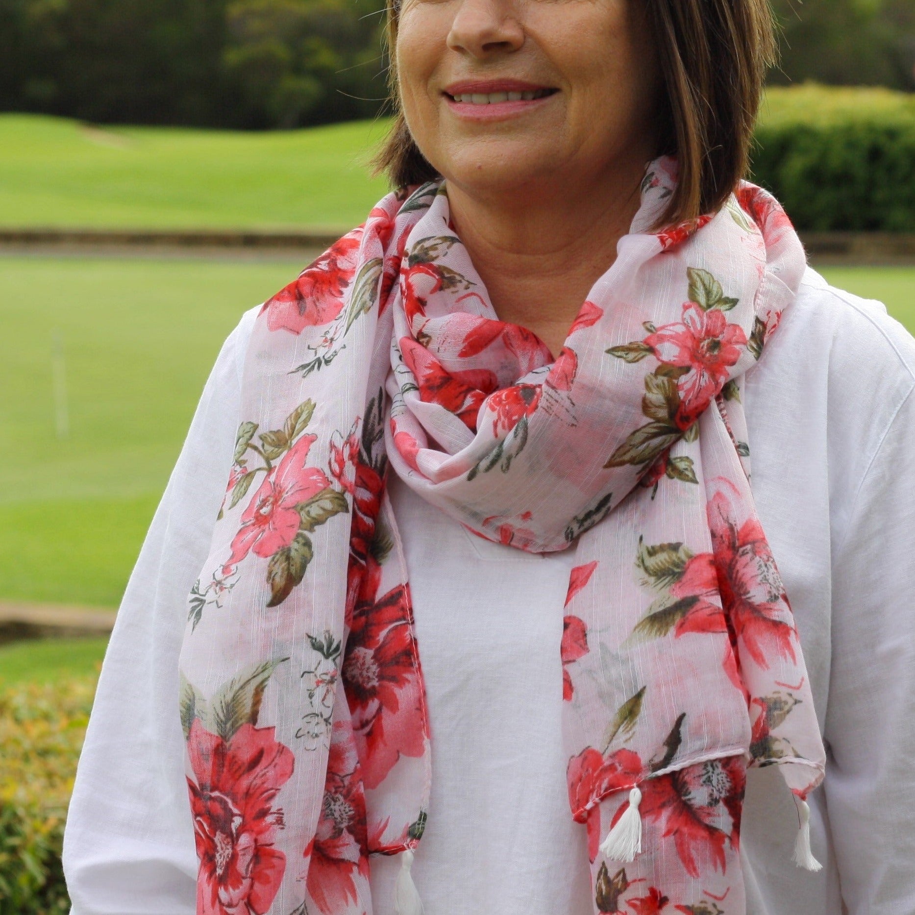 a lady wearing a pretty pale pink scarf with pink flowers and tassels