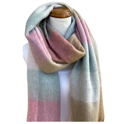 A soft, oversized scarf with a pastel gradient of pink, beige, and light blue-green, draped on a white mannequin torso with a wooden neck cap against a white background.
