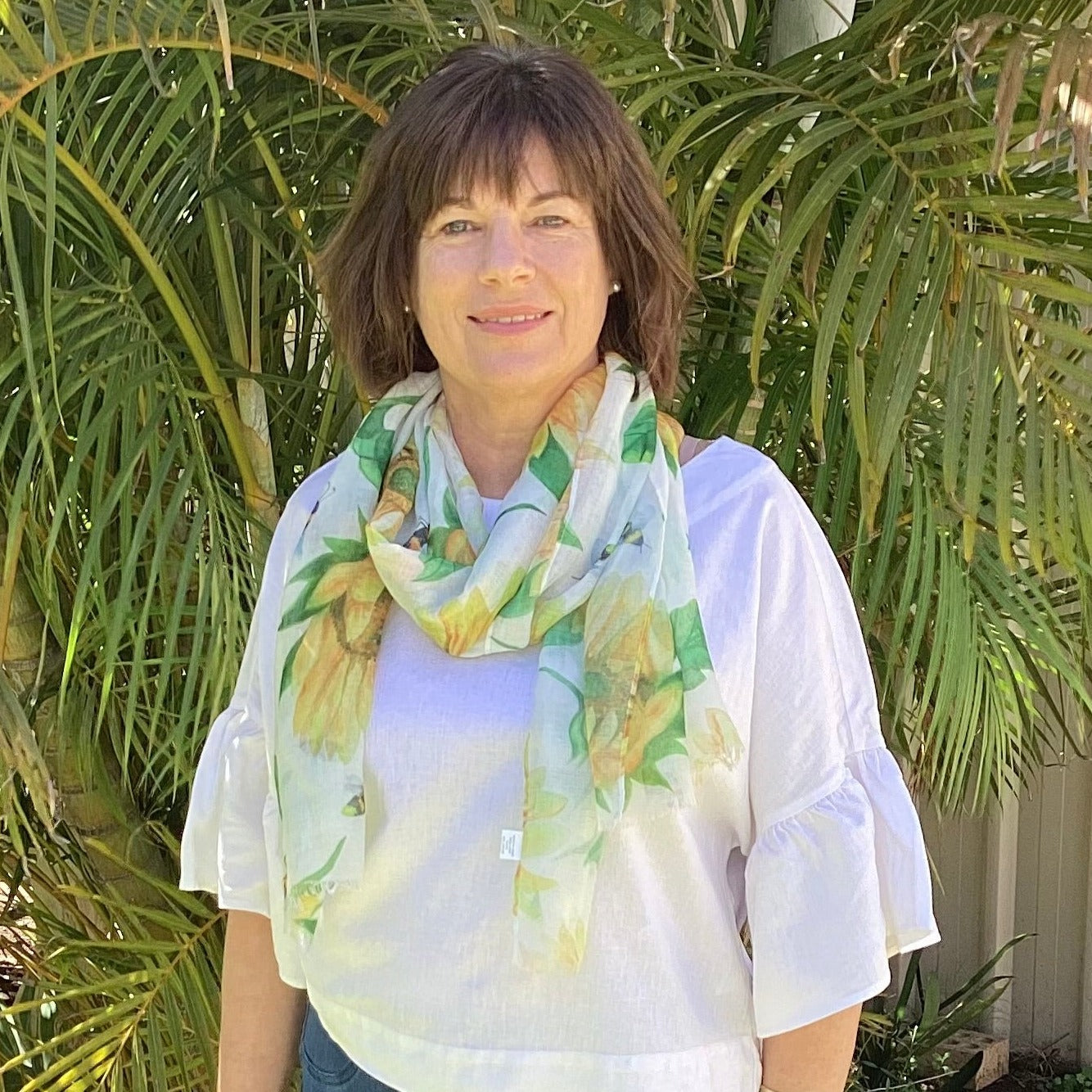 a lady wearing a white scarf with bright yellow sunflowers and bumble bees