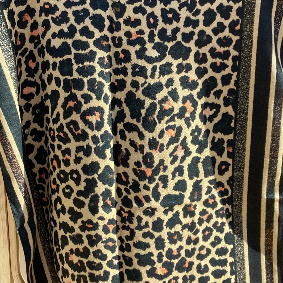 Leopard print scarf with a striped border on a white background