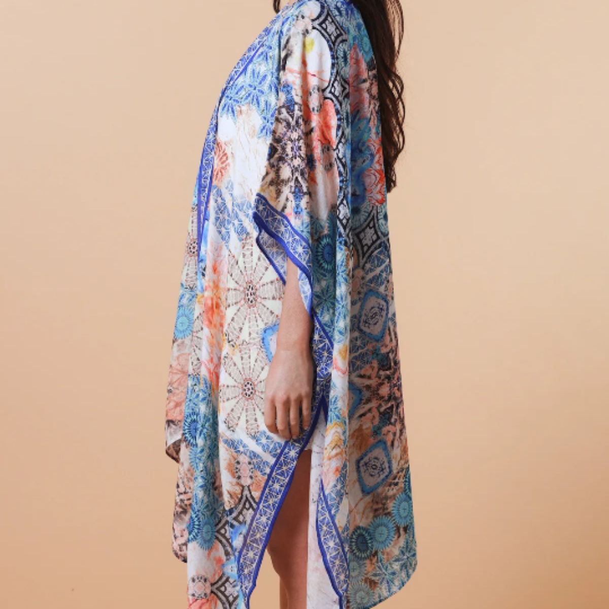 Woman wearing a colorful patterned kimono-style garment against a beige background