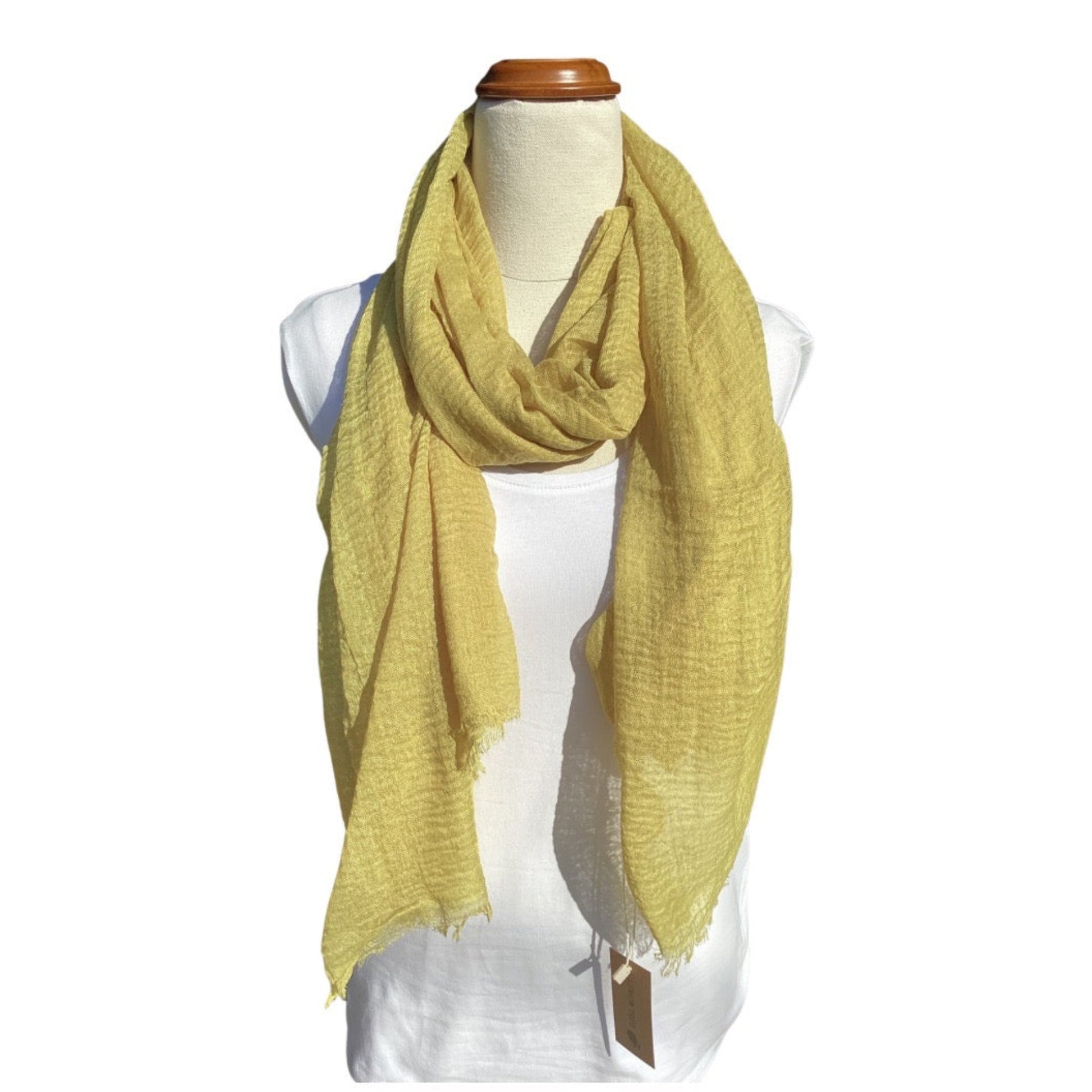 a ladies scarf that is a plain chartreuse colour and has an all over textured weave and a frayed edge on all sides