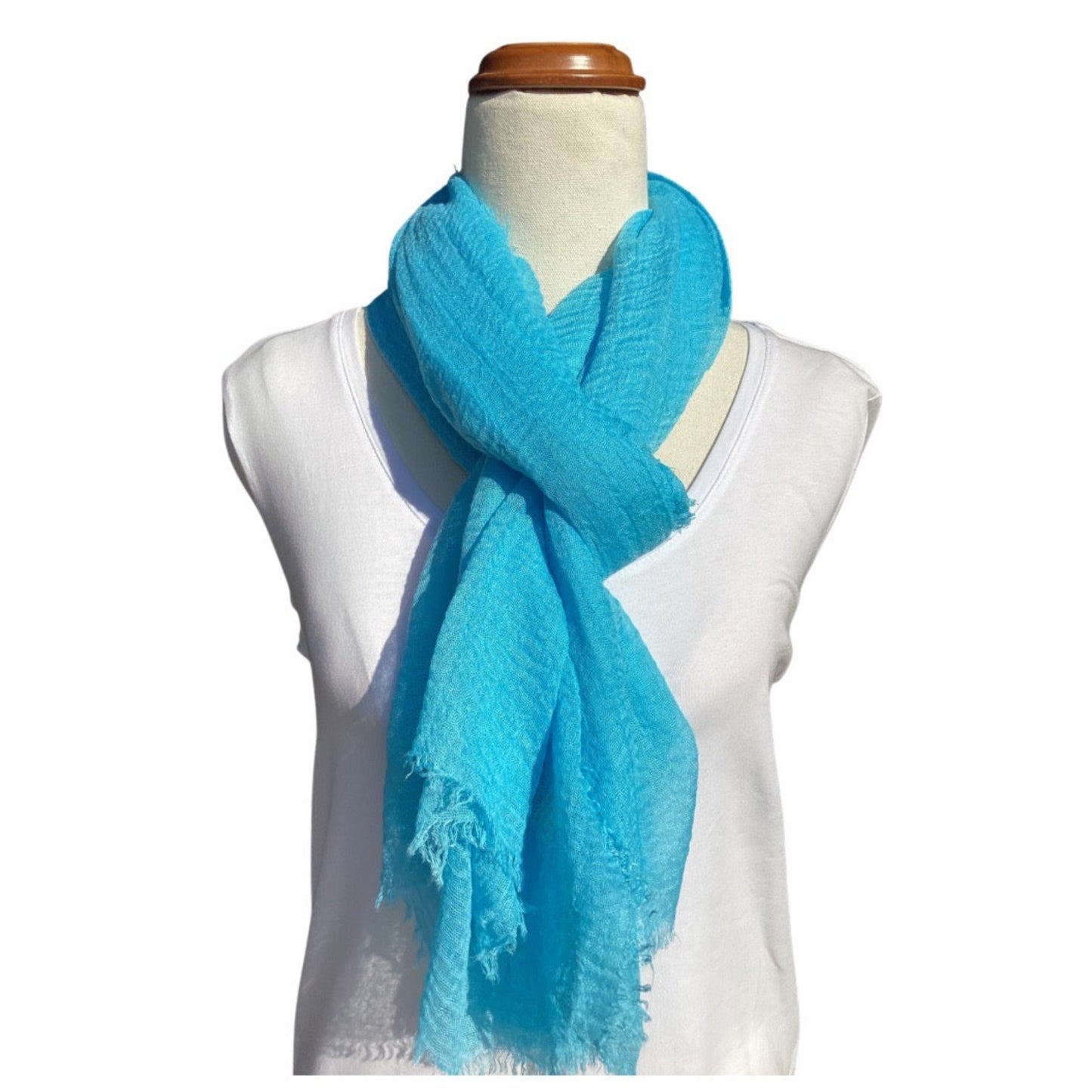 a bright blue ladies scarf that has a crinkle texture and frayed edges