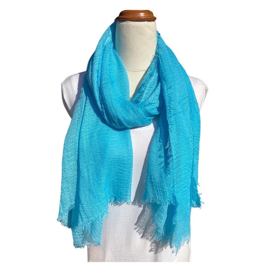 a bright blue ladies scarf that has a crinkle texture and frayed edges